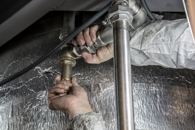 Hands completing a professional plumbing repair.