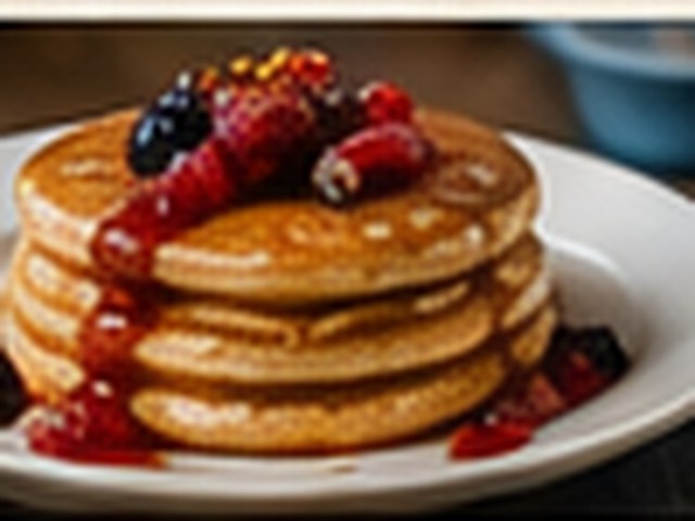 A stack of pancakes topped with berries and syrup.